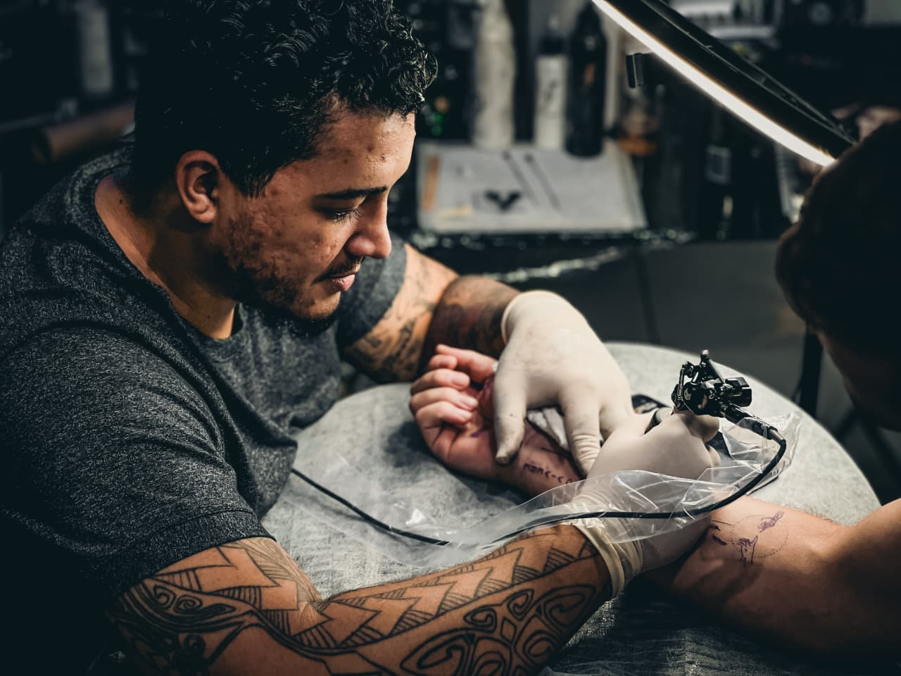 Tatuador trabalhando com luvas e equipamento protegido