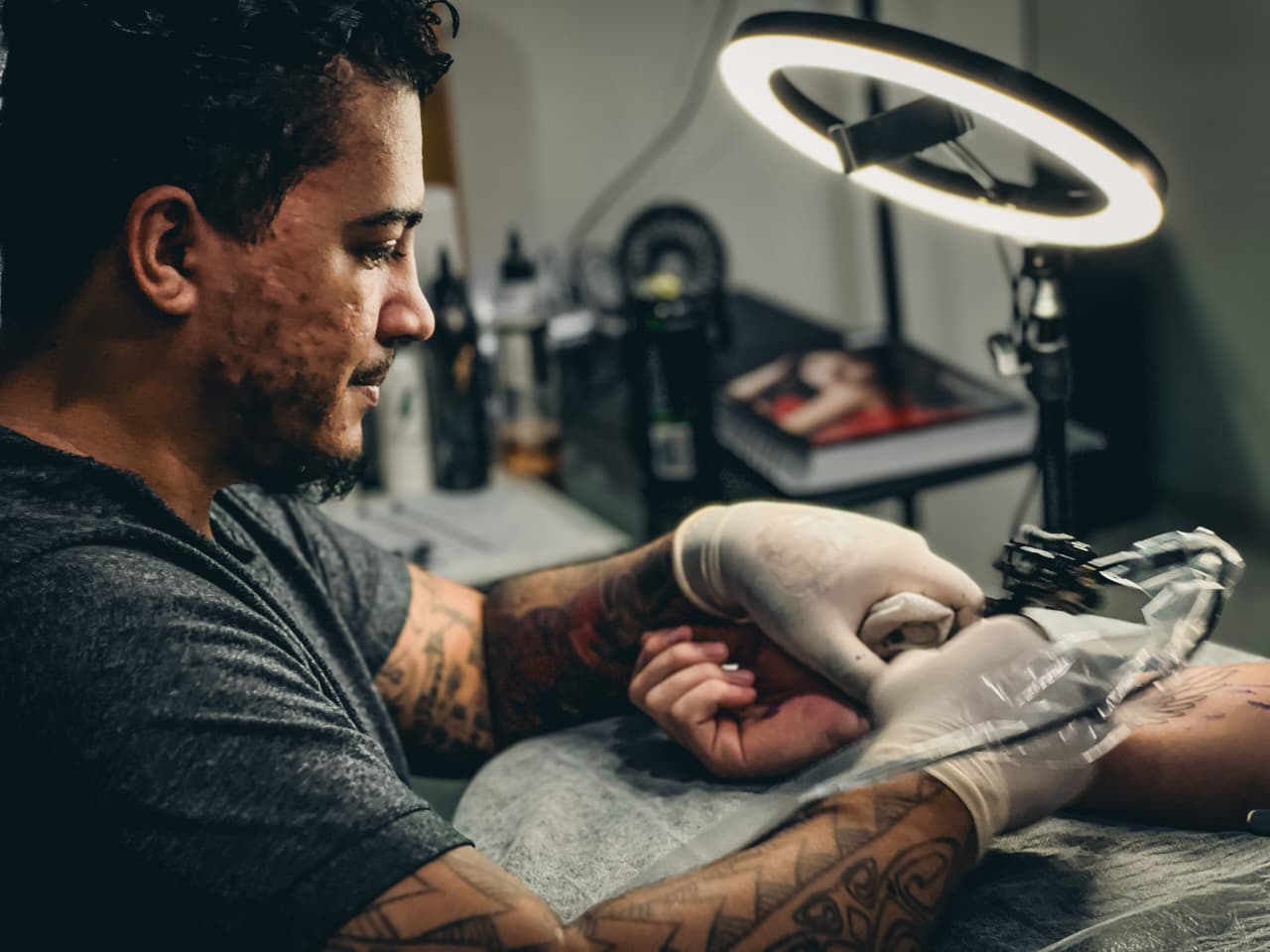 Tatuador realizando atendimento no estúdio