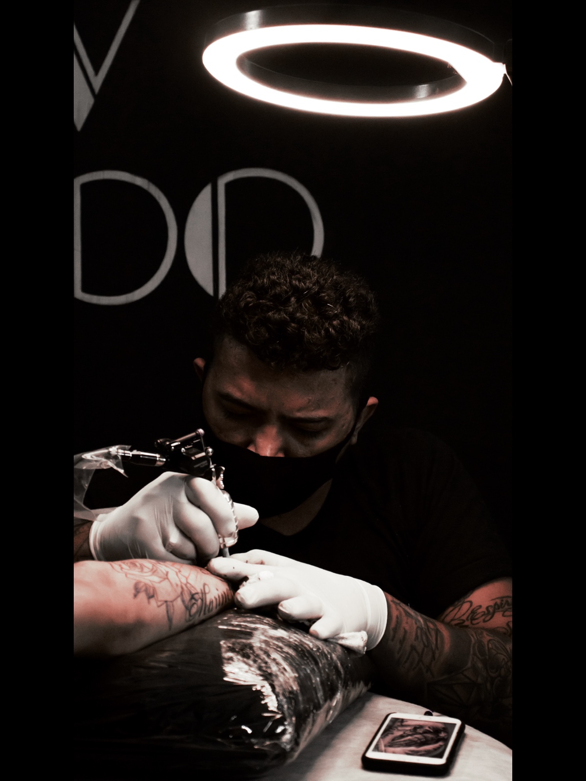 Tatuador em sessão com iluminação profissional